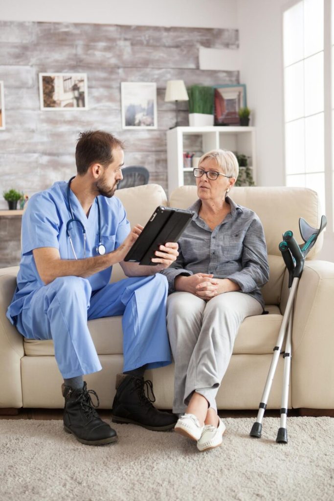 old-woman-with-crutches-nursing-home-sitting-couch-listening-male-doctor